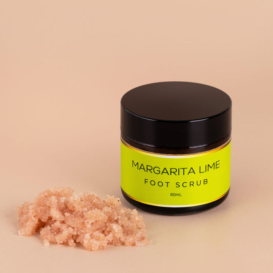 Nourishing Mana Margarita Lime Foot Scrub in a 60ml amber glass jar with mineral-rich salt scrub texture beside the jar on a beige background