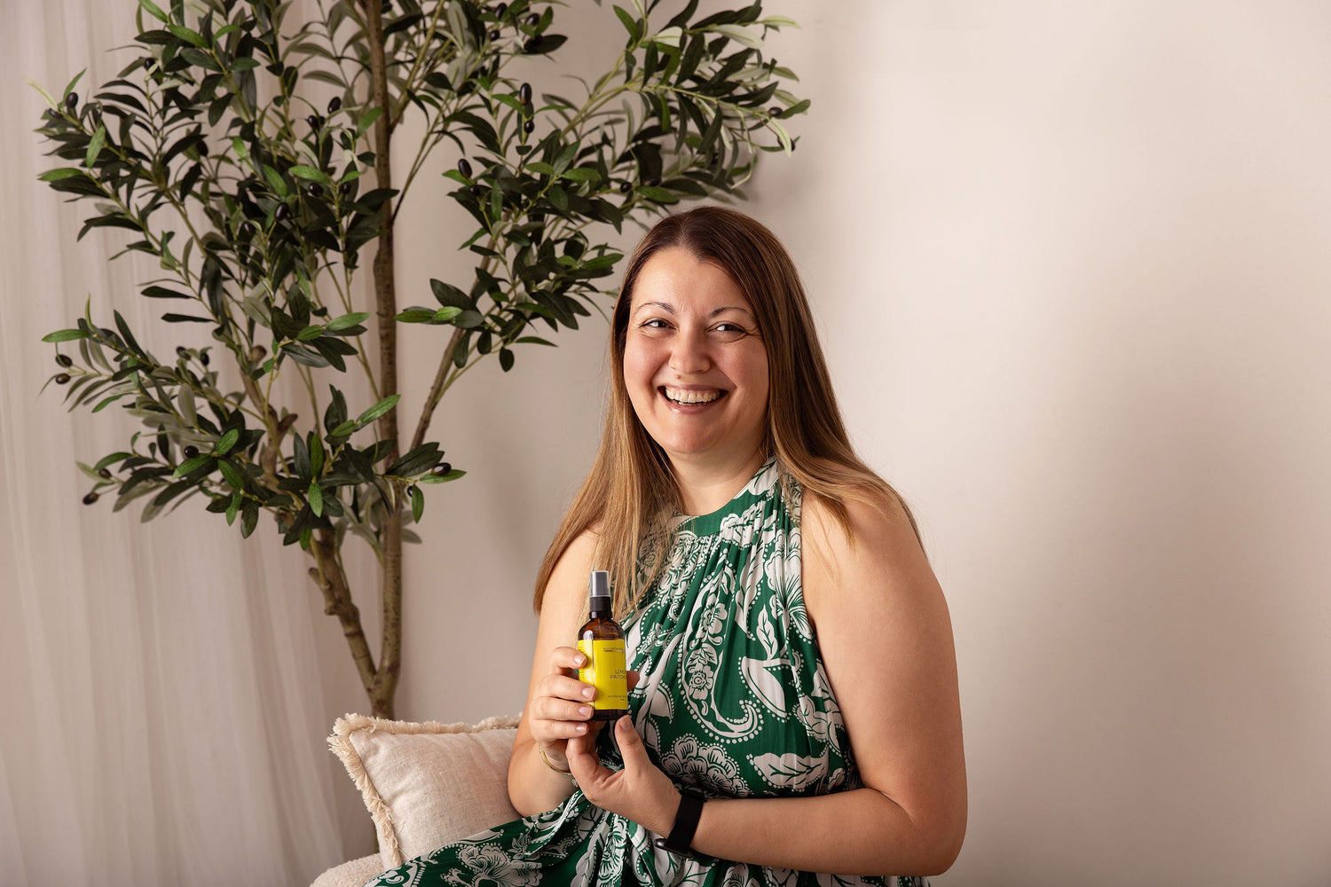 Helen, founder of Nourishing Mana, holding a handcrafted botanical body oil made in Australia for dry, changing skin.