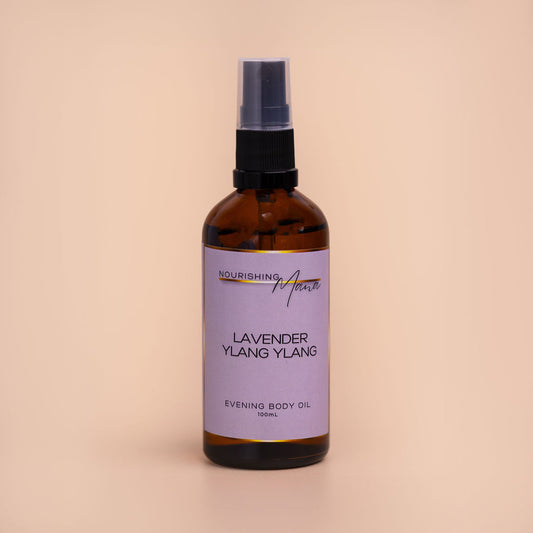 Nourishing Mana Lavender Ylang Ylang Evening Body Oil in a 100ml amber glass spray bottle on a beige background.