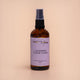Nourishing Mana Lavender Ylang Ylang Evening Body Oil in a 100ml amber glass spray bottle on a beige background.