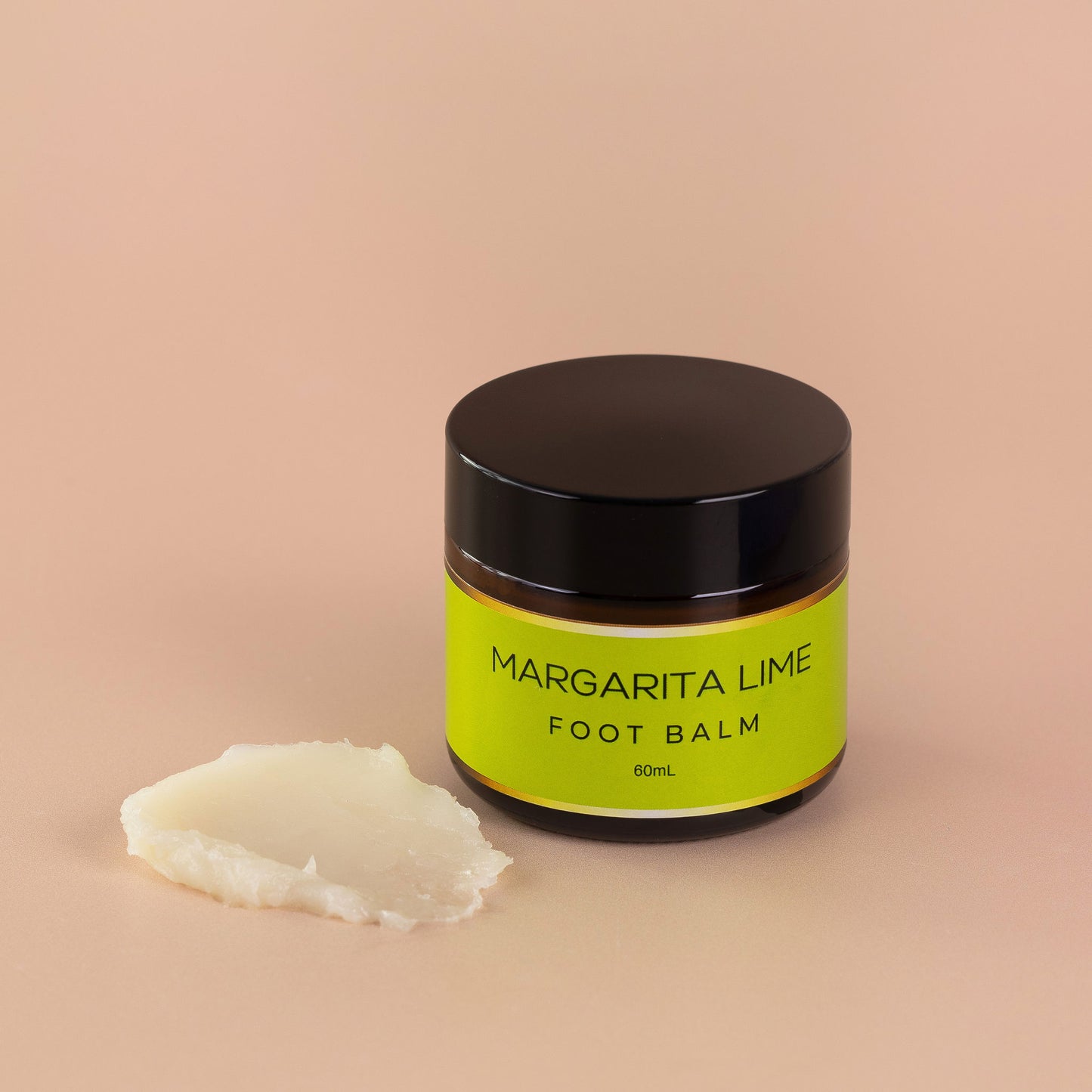 Nourishing Mana Margarita Lime Foot Balm in a 60ml amber glass jar with a sample of the balm texture beside it on a beige background.