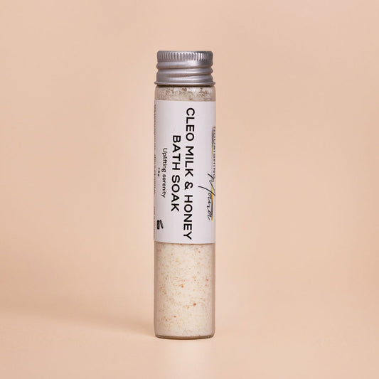 Milk and Honey Bath Soak with petitgrain and bergamot in a glass tube on a beige background.