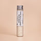 Milk and Honey Bath Soak with petitgrain and bergamot in a glass tube on a beige background.